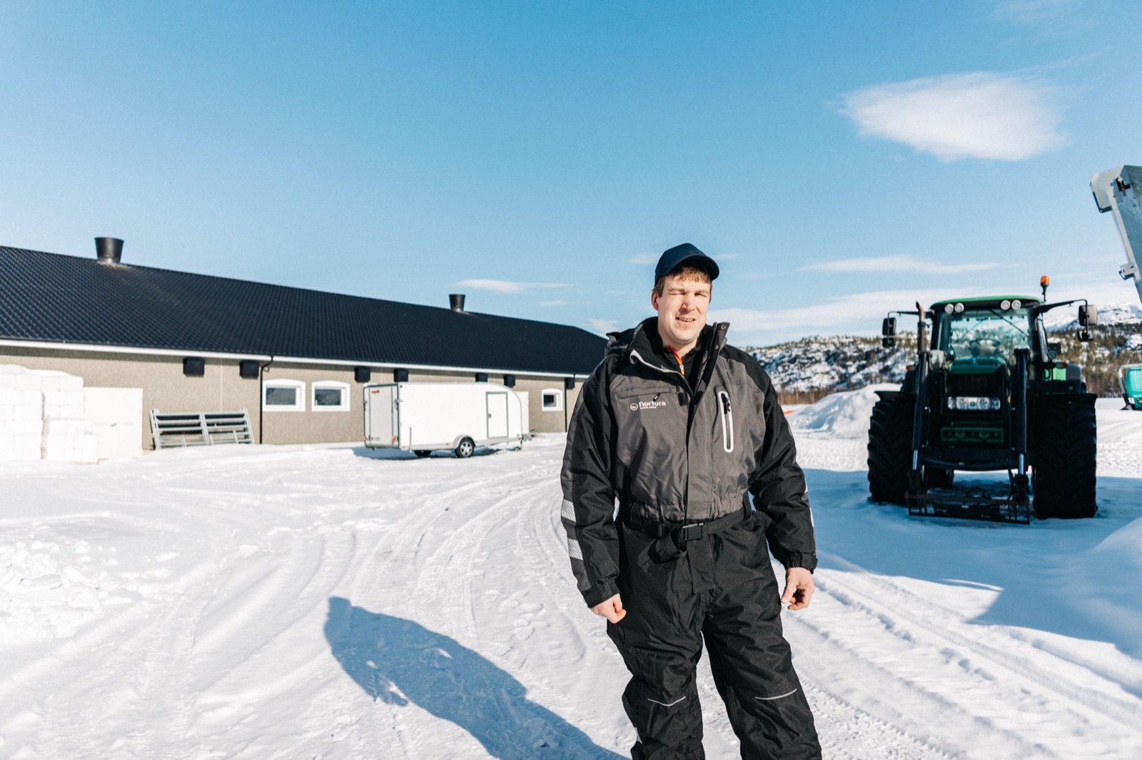 Gårdbruker Geir Ove Mannsverk foran fjøset og traktoren i Tverrelvdalen